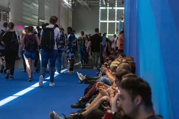 Gamescom-Besucher sitzen auf dem Boden in den Fluren und essen