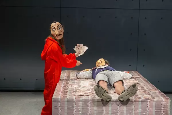 Gamescom Messebesucher auf einem Stapel Geld im Tresorraum, des Setnachbaus der Netflix Original Serie Haus des Geldes / Money Heist