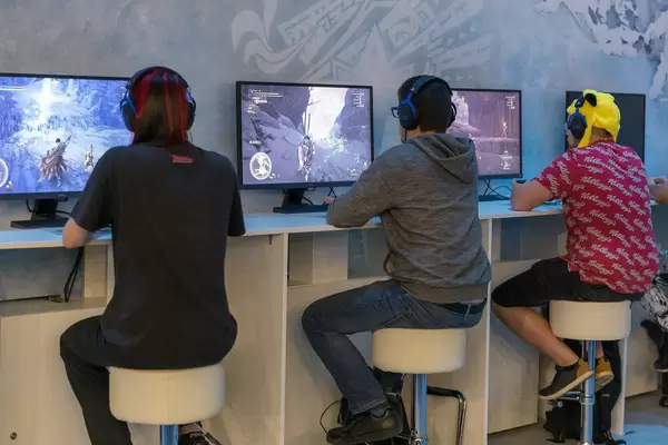 Gamescom visitors playing the Action-Adventure videogame Monster Hunter World Iceborne next to each other