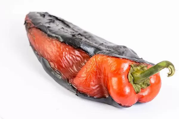 Ganze gegrillte rote Paprika auf weißem Hintergrund