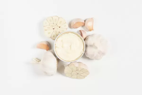 Garlics and delicious garlic sauce on white background