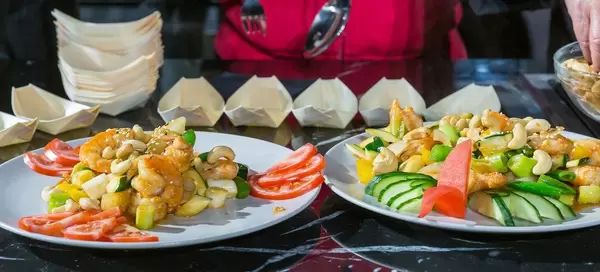 Garnelen, Nüsse und farbenfrohes Gemüse auf weißen Tellern angerichtet