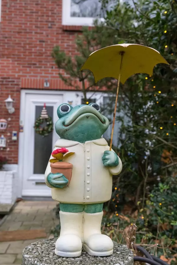 Gartendekoration aufrecht stehender Frosch mit Blumentopf und Sonnenschirm vor Hauseingang