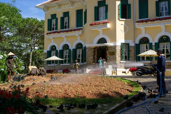 Gärtner bepflanzen und wässern den Garten vor dem Bao Dai Königspalast in Da Lat, Vietnam