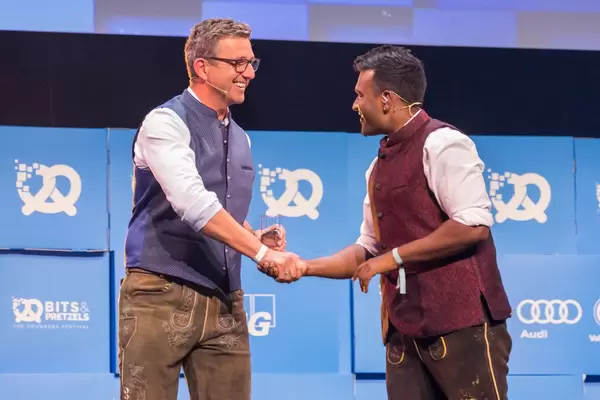 Gastgeber Dan Ram begrüßt Hans Sigl auf der Bühne von der Gründerkonferenz Bits & Pretzels in München