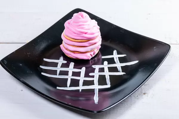Gebäck mit pinker Sahne auf schwarzem Teller