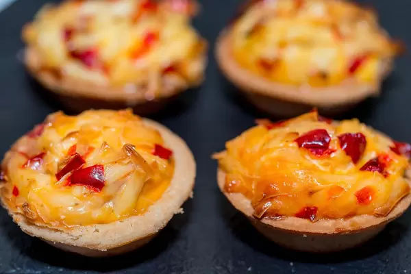 Gebackene Küchlein mit Käse auf schwarzem Backblech