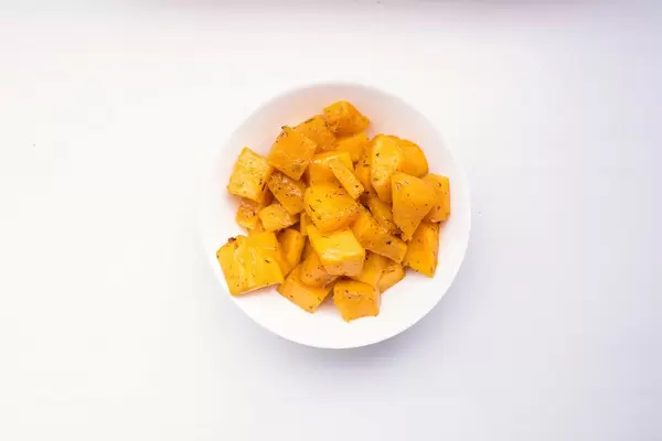 Gebackene Kürbiswürfel in einer weißen Schale auf weißem Hintergrund