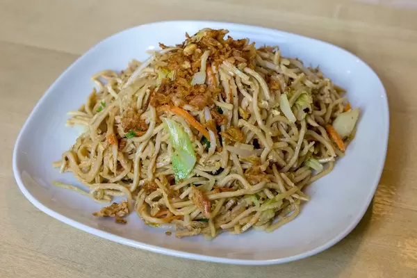 Gebratene Nudeln mit Ei, Möhren und Lauch, als vegetarische Speise, serviert auf einem hellen Teller