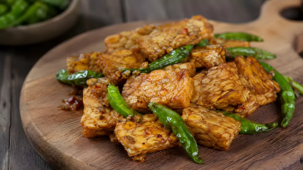 Gebratenes Tempeh mit grünen Chilischoten auf Holzbrett