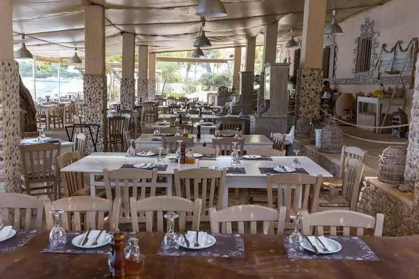 Gedeckte Tische mit Platzdeckchen in einem schicken Restaurant mit Meerblick