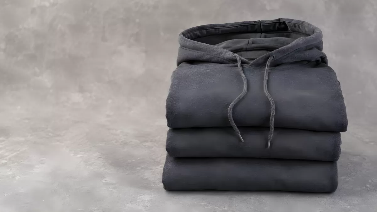 Gefaltete graue Hoodies ordentlich gestapelt auf Beton