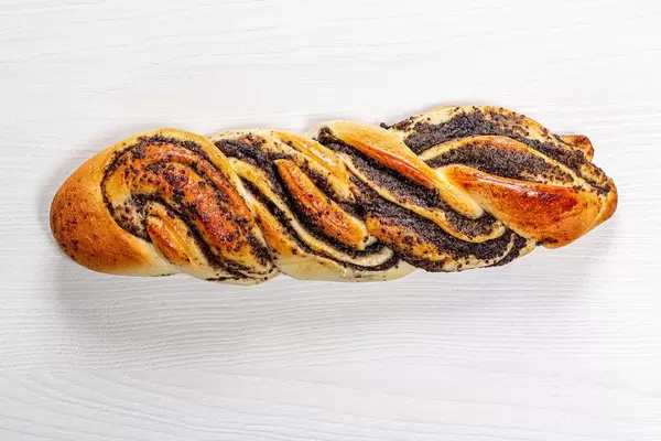 Geflochtener süßer Kranz mit Mohnsamen auf einem weißen Holztisch top-view