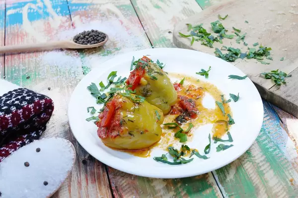 Gefüllte Paprika mit Fleisch nach griechischer Art. Bunter hölzerner Hintergrund im Vintage-Stil