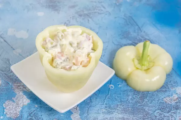 Gefüllte Paprika mit Gemüsesalat, auf einer blauen Oberfläche