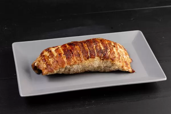 Gefülltes Steak auf weißem Teller auf schwarzem Untergrund