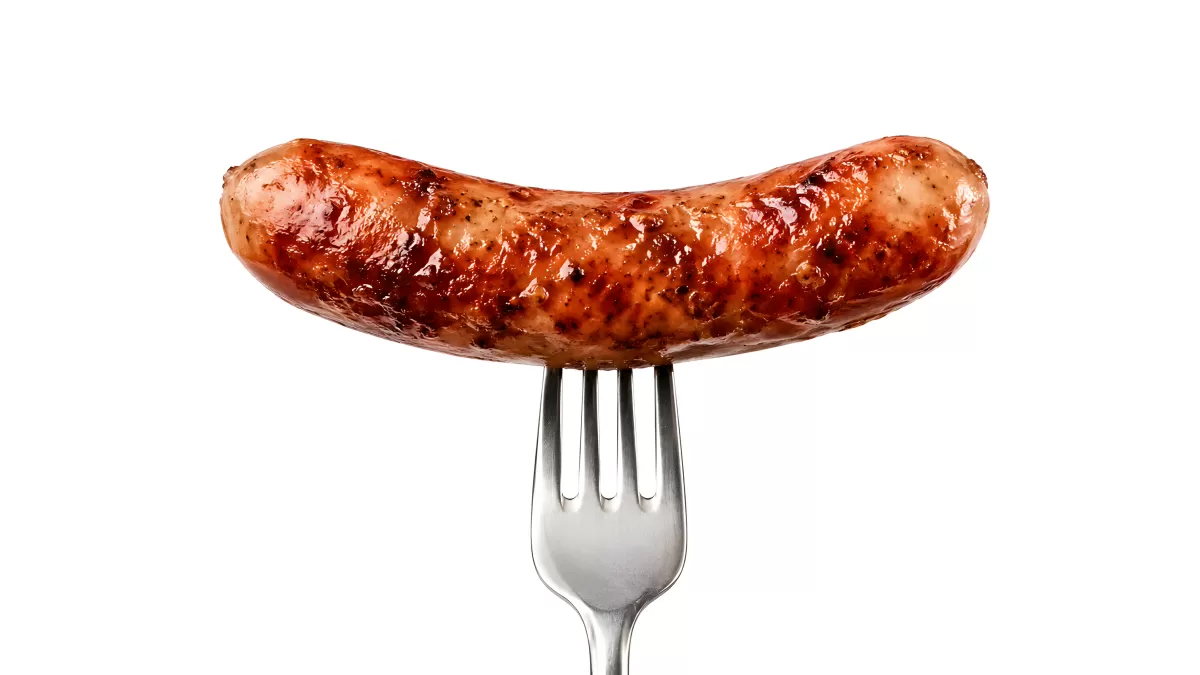 Gegrillte Bratwurst auf einer Gabel vor weißem Hintergrund
