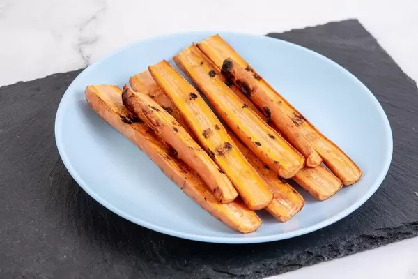 Gegrillte Karottensticks auf einer schwarzen Schiefersteinplatte