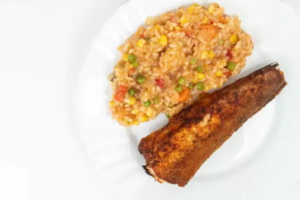 Gegrillter Seehecht mit Risotto auf weißem Teller aus oben fotografiert