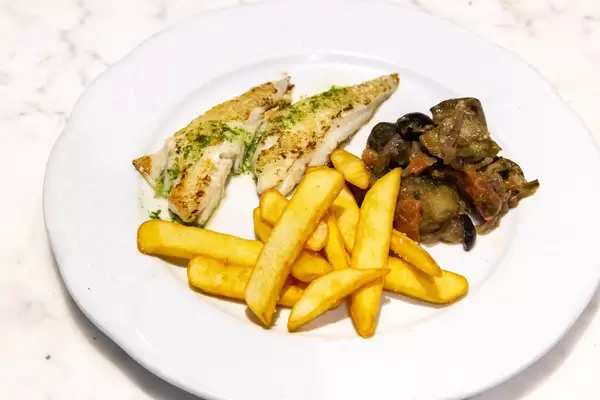 Gegrilltes Schapperfilet mit Pommes und Gemüse auf einem weißem Teller