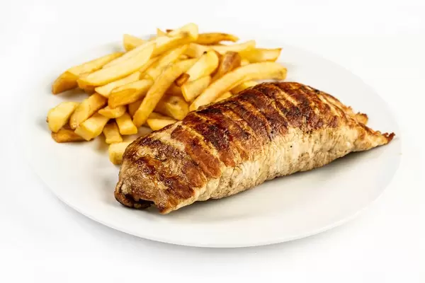 Gegrilltes Schweinefleisch mit Füllung und Pommes auf einem weißen Teller