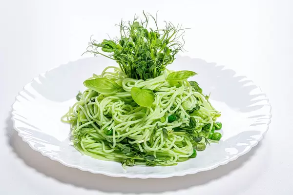 Gekochte Spaghetti mit frischen Bohnen Sprossen und jungen Bohnen auf einem weißen Teller