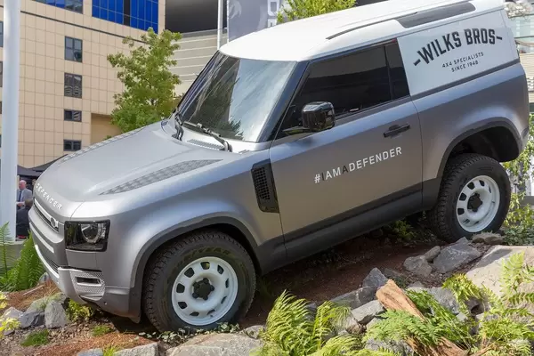 Geländewagen Land Rover Defender draußen auf unwegsamen Gelände, mit Wilks Bros Schriftzug, Pivi Pro Technologie und #Iamadefender