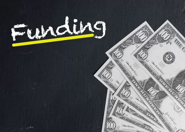Gelb unterstrichenes Wort FUNDING (Finanzierung) mit Dollarnoten auf schwarzem Hintergrund
