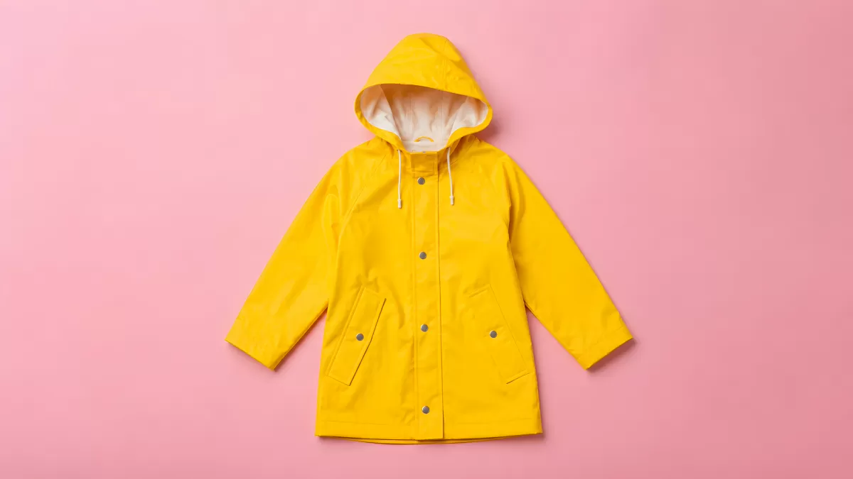 Gelbe Regenjacke mit Kapuze auf rosa Hintergrund