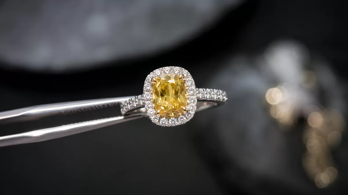 Gelbem Diamantring in Pinzette gehalten – Nahaufnahme