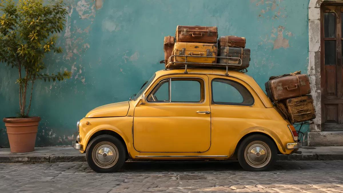 Gelber Fiat 500 mit Vintage-Koffern auf Kopfsteinpflaster