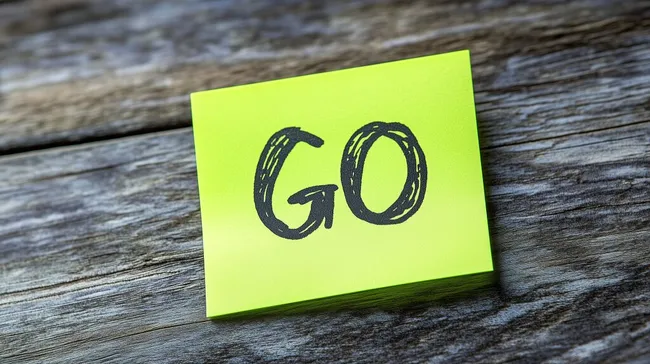 Gelber Notizzettel mit Schriftzug 'GO' auf Holztisch