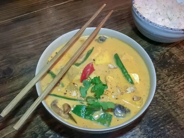 Gelbes Curry mit Pilzen, Paprika und Bohnen dekoriert mit Petersilie mit Reis Essstäbchen