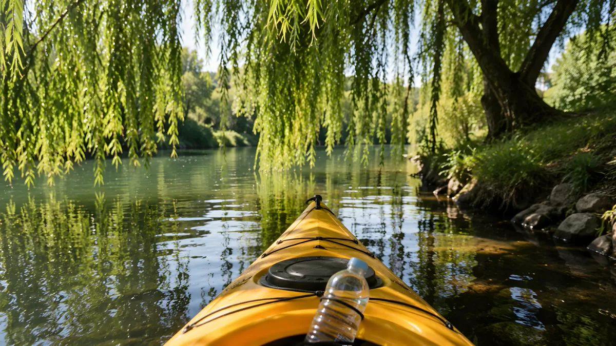Gelbes Kajak auf ruhigem Fluss unter Weidenbäumen