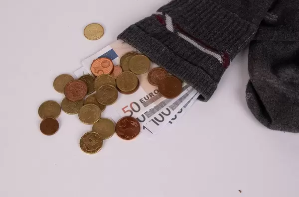 Geldscheine und Kleingeld stecken in einem alten Strumpf