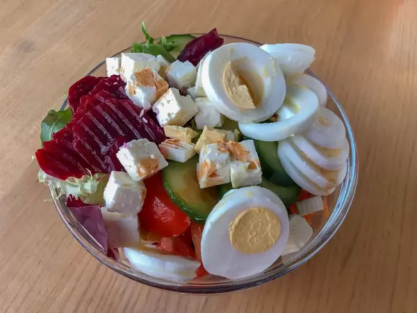 Gemischter Salat aus Ei, roter Bete, Fetakäse, Tomaten, Gurken und Karotten in Glasschale