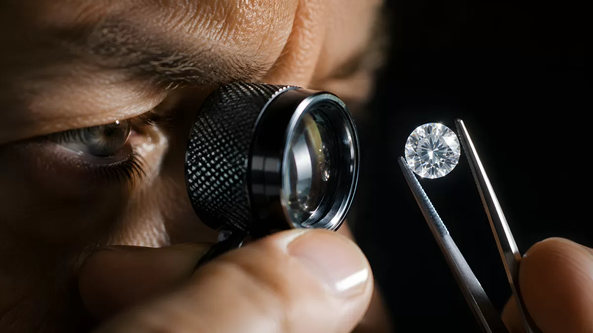 Gemmologe prüft Diamant mit Lupe und Pinzette
