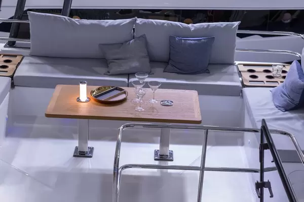 Gemütlich ausgestattetes Heck eines Bootes mit Tisch, Sitzbänken und Getränkehaltern