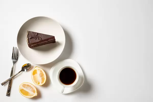 Gemütliche Pause mit Kaffee und Torte: Aufnahme von oben mit angeschnittener Zitrone und Besteck