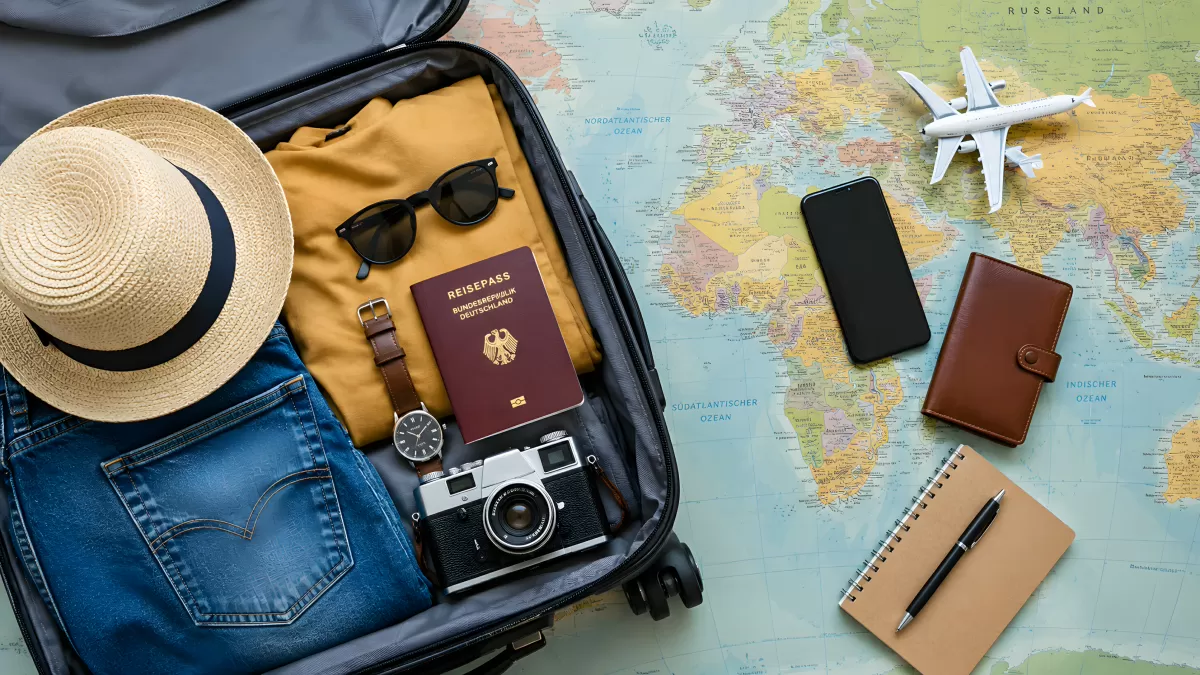 Geöffneter Koffer mit Reiseutensilien auf Weltkarte
