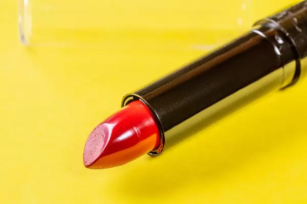 Geöffneter Lippenstift für knallrote Lippen isoliert vor gelbem Hintergrund