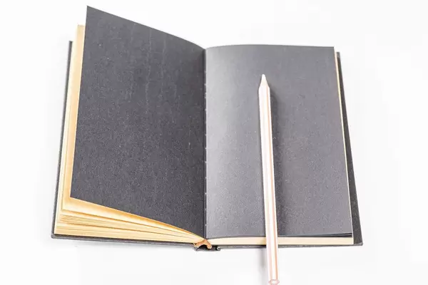 Geöffnetes Notizbuch mit schwarzen Seiten und einem weißen Stift