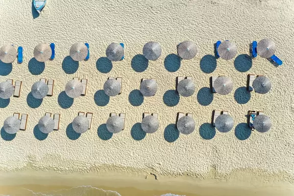 Geometric beach design: overhead drone shot of rows of thatched beach umbrellas at Plaka, Naxos