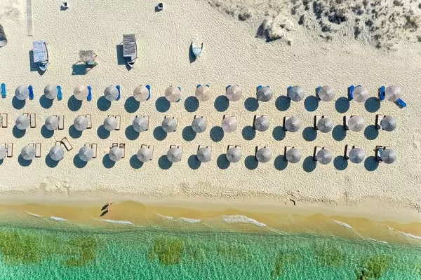 Geometrie am Strand: Overhead Luftbild von Sonnenschirmen aus Stroh. Plaka, Naxos