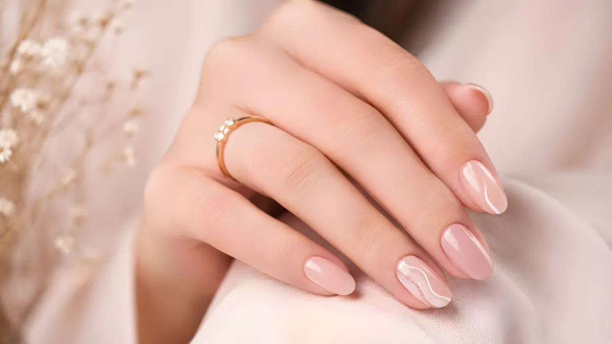 Gepflegte Hand mit zartrosa Nägeln und Goldring