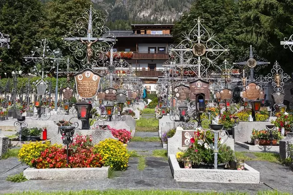 Gepflegter Friedhof in Alpbach mit Blumen und Grabsteinen mit Metallkreuzen und Fotos der Toten