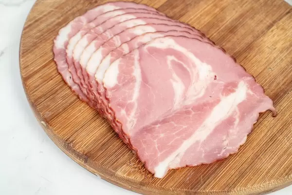 Geräucherter Schweinenacken auf einem Holzbrettchen in der Küche