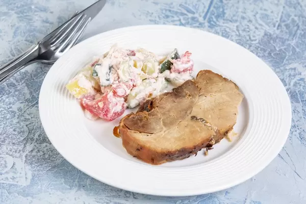 Gericht aus Schweinekotelett mit serbischem Schopska-Salat aus Gemüse und eingelegtem Käse