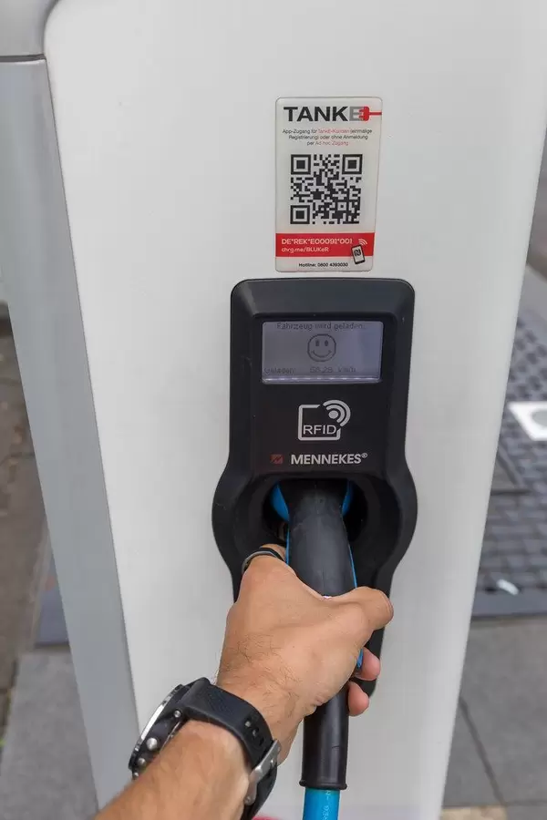 German TankE network for electric vehicles: men hand holds the plug in while his car is charging at a RheinEnerie station in Cologne