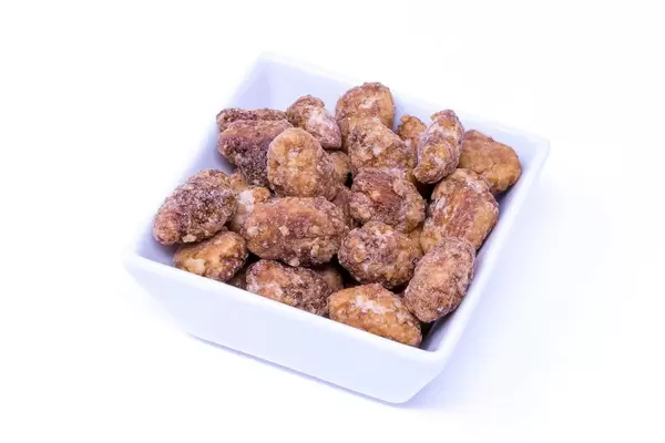 Geröstete Mandeln in quadratischer Schale auf weißem Hintergrund